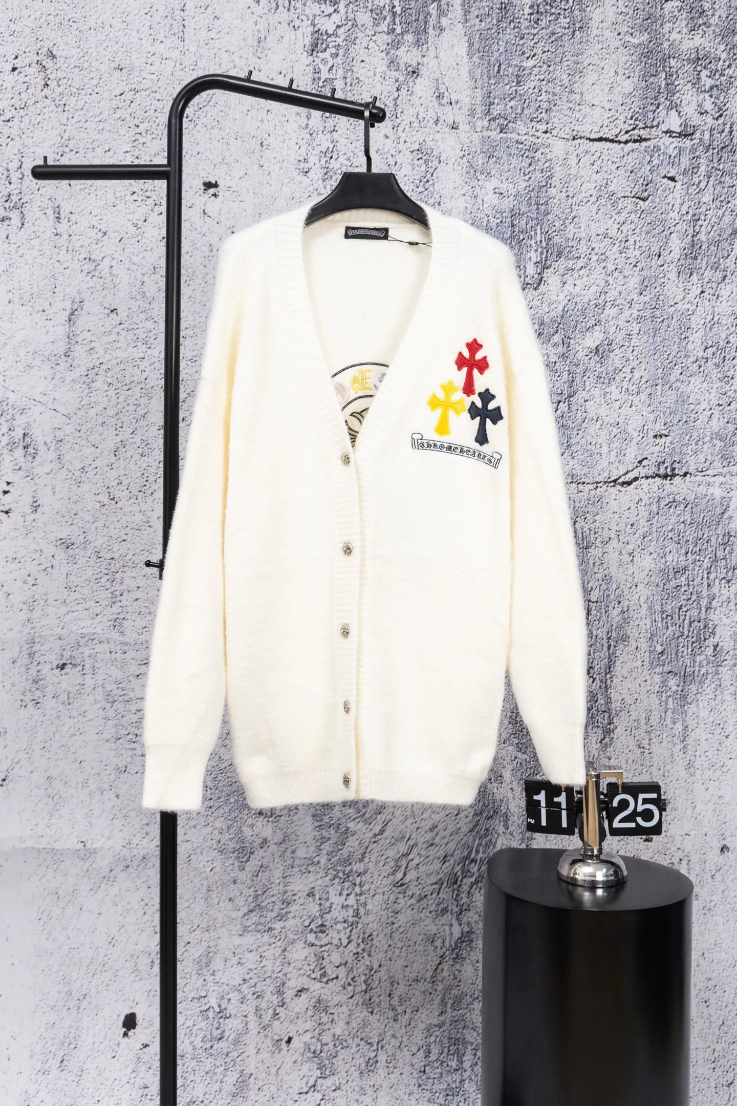 P300 Chrome Hearts CH Chrome Hearts 2026 new cross loose knitted V-neck cardigan Fabric: Made of plush textured knitted material, soft to the touch and with a lazy atmosphere; Decoration: Red, yellow, and black cross ornaments on the chest, paired with brand logo patches, which are iconic elements of street fashion brands (such as Chrome Hearts style), enhancing visual recognition; Version: Loose version + single-row metal button design, combining casual feeling and practicality. 2. Style and Adaptation Style: It combines dark street style and gentle knitted texture, which belongs to the tone of "sweet and cool mix"; Scenario: Can be worn with a T-shirt/suspender to create a daily street look, or can be layered with a shirt for light casual wear. Color: Black White Size: M L XL